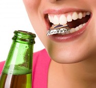 Close up of woman opening a bottle with her teeth