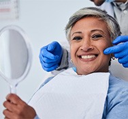 Senior woman smiling while dentist stands behind her